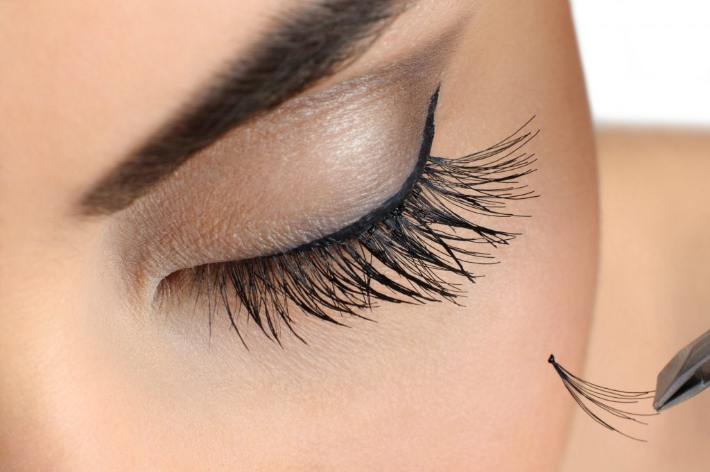close up of closed eye with fabulous makeup getting individual eyelash extensions