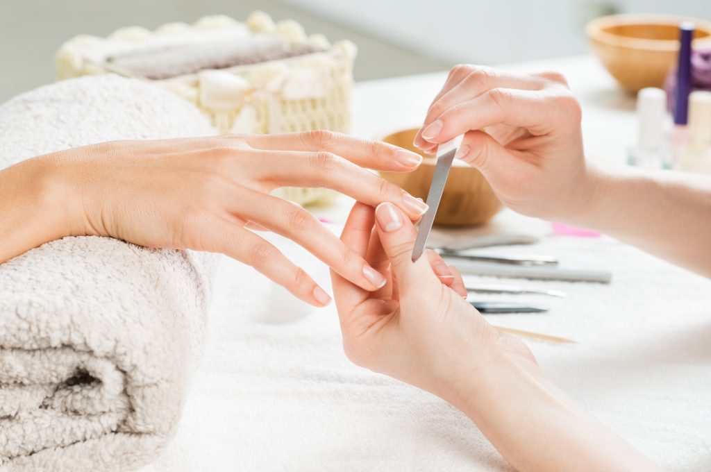 close up of a woman's hand getting manicure at what looks like a nail salon
